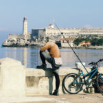 Pescadores en bicicleta. Canal de la bahía de La Habana. El Catillo del Morro.