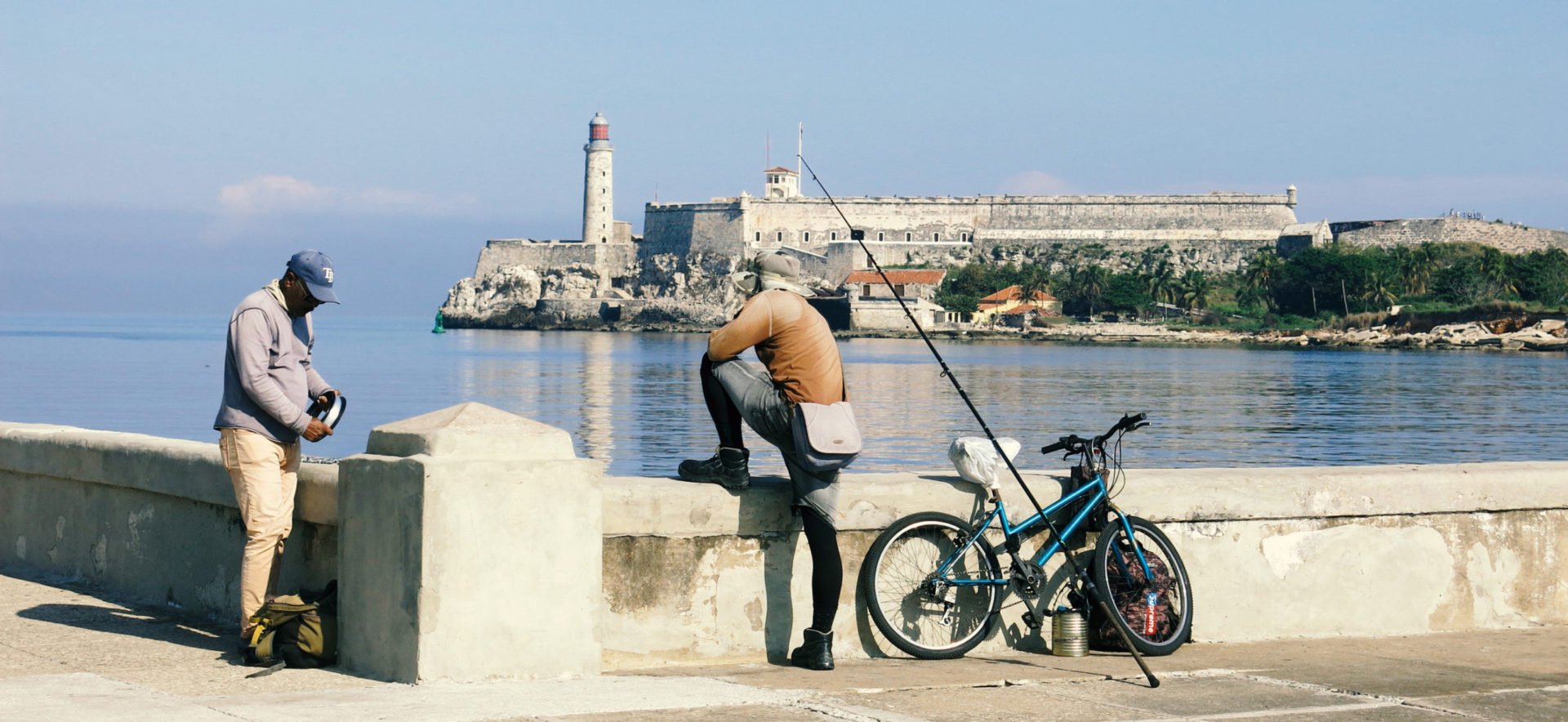 Pescadores en bicicleta. Canal de la bahía de La Habana. El Catillo del Morro.