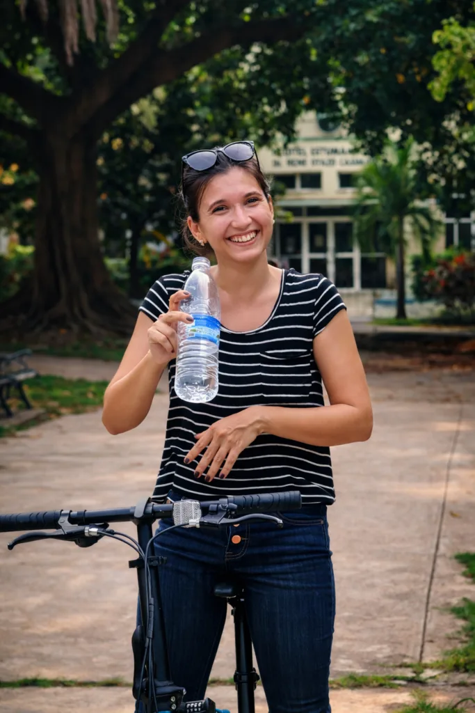 chica sonrie dirante la clase de ciclismo y sostiene una botella de agua